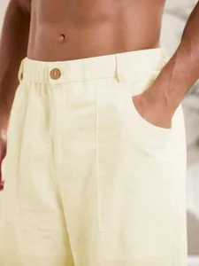 Dettaglio dei pantaloni da uomo in cotone e lino con bottone in vita e tasca