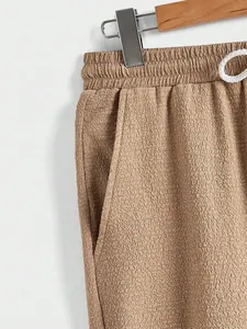 Close-up of men's khaki joggers showing textured fabric, drawstring waist, and side pocket.