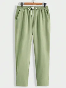 Detail view of light green casual pants featuring textured fabric and drawstring waist