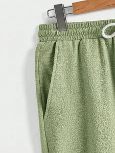 Close-up of green textured fabric on men's casual pants with drawstring