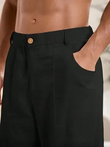 Primo piano di pantaloni in lino nero da uomo con bottone in legno e tasca laterale.