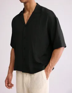 Detail view of a black textured short-sleeved men's shirt featuring a loose fit and lapel collar