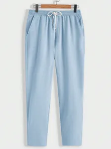 Close-up of light blue textured casual trousers with elastic drawstring waist.