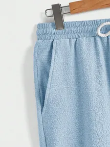 Close-up detail of light blue textured fabric on men's casual elastic waist trousers.