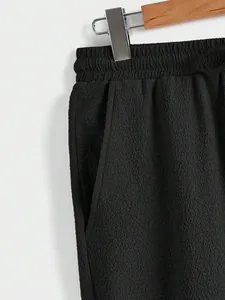 Close-up detail of black textured casual pants showing elastic waistband and side pocket