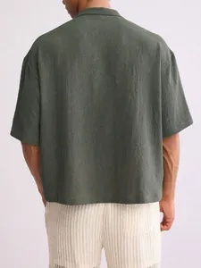 Back view of men's loose olive green short-sleeve shirt with textured fabric detail