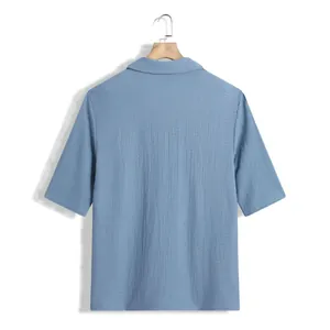 Vue arrière d'une chemise bleue à manches courtes pour homme en tissu texturé sur un cintre.