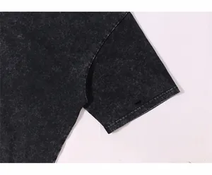 Gros plan sur la couture de la manche et la texture d'un t-shirt gris foncé délavé à l'acide