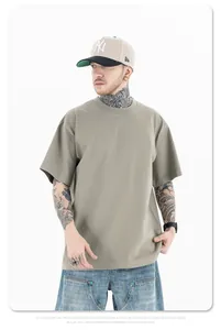 Man in een kaki 260g katoenen oversize T-shirt met verlaagde schouders en losse pasvorm