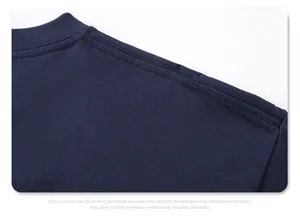 Close-up van de schoudernaad met dubbele naald op een marineblauw katoenen T-shirt.