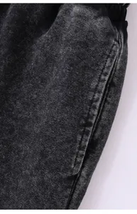 Gros plan sur la texture du tissu délavé et les détails de la poche sur le jogging noir