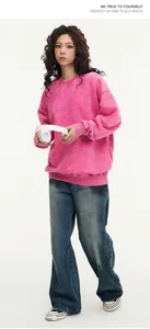 Detail shot of a pink acid-wash oversized sweatshirt worn by model with headphones