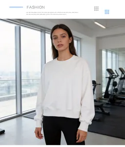 Detail view of a white cropped crewneck sweatshirt worn by a model in a gym.