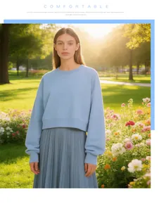 Close-up of a stylish woman wearing a light blue cropped crewneck sweatshirt in a park