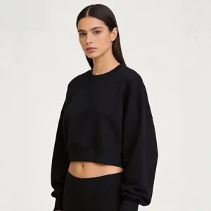 Modern black cropped long sleeve sweatshirt with round neck shown on model in studio setting