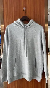 Λεπτομέρεια γκρι oversized φούτερ με κουκούλα, χαμηλούς ώμους και μπροστινή τσέπη
