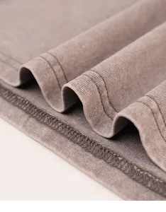 Macro detail of vintage acid wash cotton t-shirt fabric showing high-quality stitching.