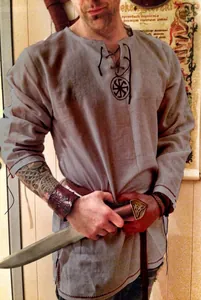 Detail of a mens grey medieval linen tunic with lace-up neck and Slavic symbol engraving.