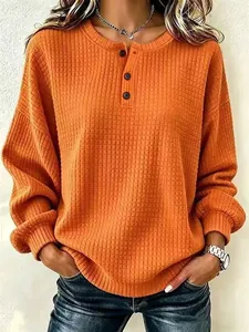 Detail van de oranje wafelgebreide textuur op het casual damessweatshirt met knopen