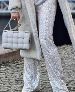 Detailed view of silver sequined straight leg trousers showing shimmering light reflections