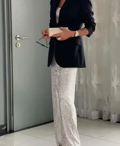 Close-up of elegant silver sequin straight-leg trousers with black blazer