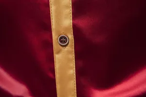 Nahaufnahme eines glatten burgunderfarbenen Satinhemds mit goldener Knopfleiste