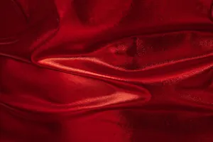 Macro detail of red shiny metallic fabric texture showing folds and light reflection