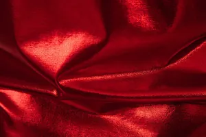 Macro view of high-quality shiny metallic red fabric texture showing luster and drape
