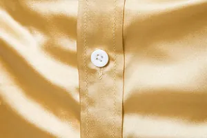 Primer plano de la textura de camisa de satén dorado con detalle de botón blanco