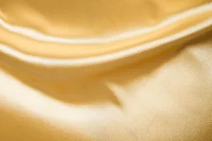 Primer plano de tela de satén dorado de alta calidad con brillo de seda y ondas