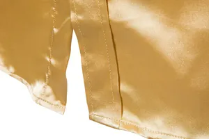 Detalle de camisa de satén dorado con abertura lateral y costura de calidad