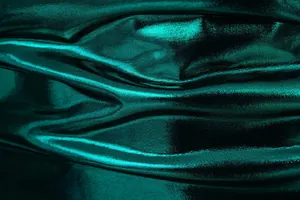 Macro view of shiny dark green metallic fabric showing luxurious texture and drape.