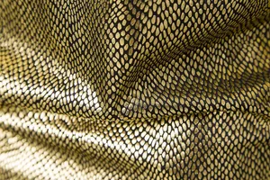 Detailopname van de gouden stof met slangenprint en een glanzend metallic effect