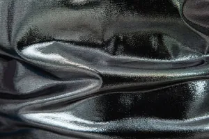 Close-up detail of shiny metallic silver-black fabric texture with light reflections.