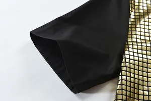 Close-up of black short sleeve shirt with gold sequin metallic grid pattern texture.