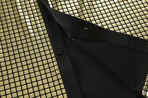 Macro detail showing the shiny gold sequin pattern on a black men's dress shirt fabric