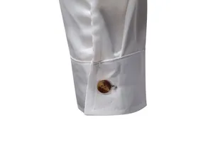Dettaglio del polsino di una camicia da uomo in raso bianco con bottone elegante.