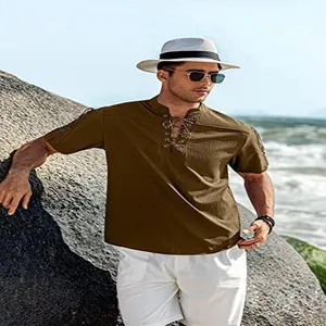 Mann trägt ein braunes, geschnürtes Hippie-Hemd mit kurzen Ärmeln an einem felsigen Strand