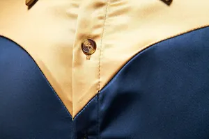 Dettaglio macro della camicia di raso da uomo con design color block oro e blu