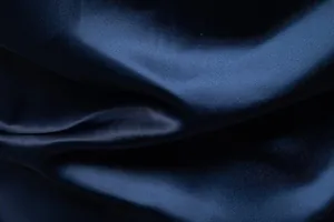 Primo piano macro del tessuto in raso blu navy che mostra la sua lucentezza setosa e morbidezza