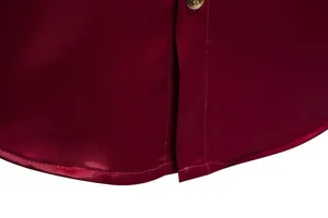 Vista dettagliata dell'orlo curvo e del tessuto di raso setoso di una camicia bordeaux da uomo.
