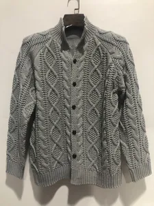 Dettaglio del pesante cardigan grigio da uomo con intricati motivi a trecce e collo a lupetto