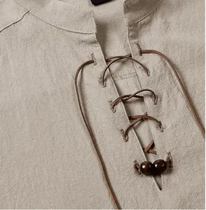 Macro view of khaki men's henley shirt collar featuring lace-up detail and wooden beads.