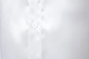 Primer plano de la textura brillante de la tela de camisa de satén blanco y botón