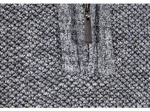 Detailed macro view of the metal half-zipper on a grey textured knit winter sweater