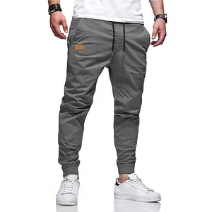 Pantaloni cargo grigi da uomo con coulisse in vita e polsini elastici su sfondo bianco.