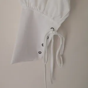 Close-up view of a white medieval shirt sleeve cuff featuring metal eyelets and laces
