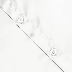Macro-detailweergave van een wit satijnen discohemd met glanzende stof en witte knopen