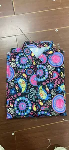 Folded detail of 70s disco retro floral shirt featuring vibrant paisley pattern on black