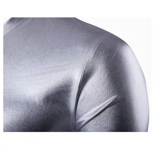 Dettaglio ravvicinato del tessuto metallico argento lucido di una maglietta slim da uomo